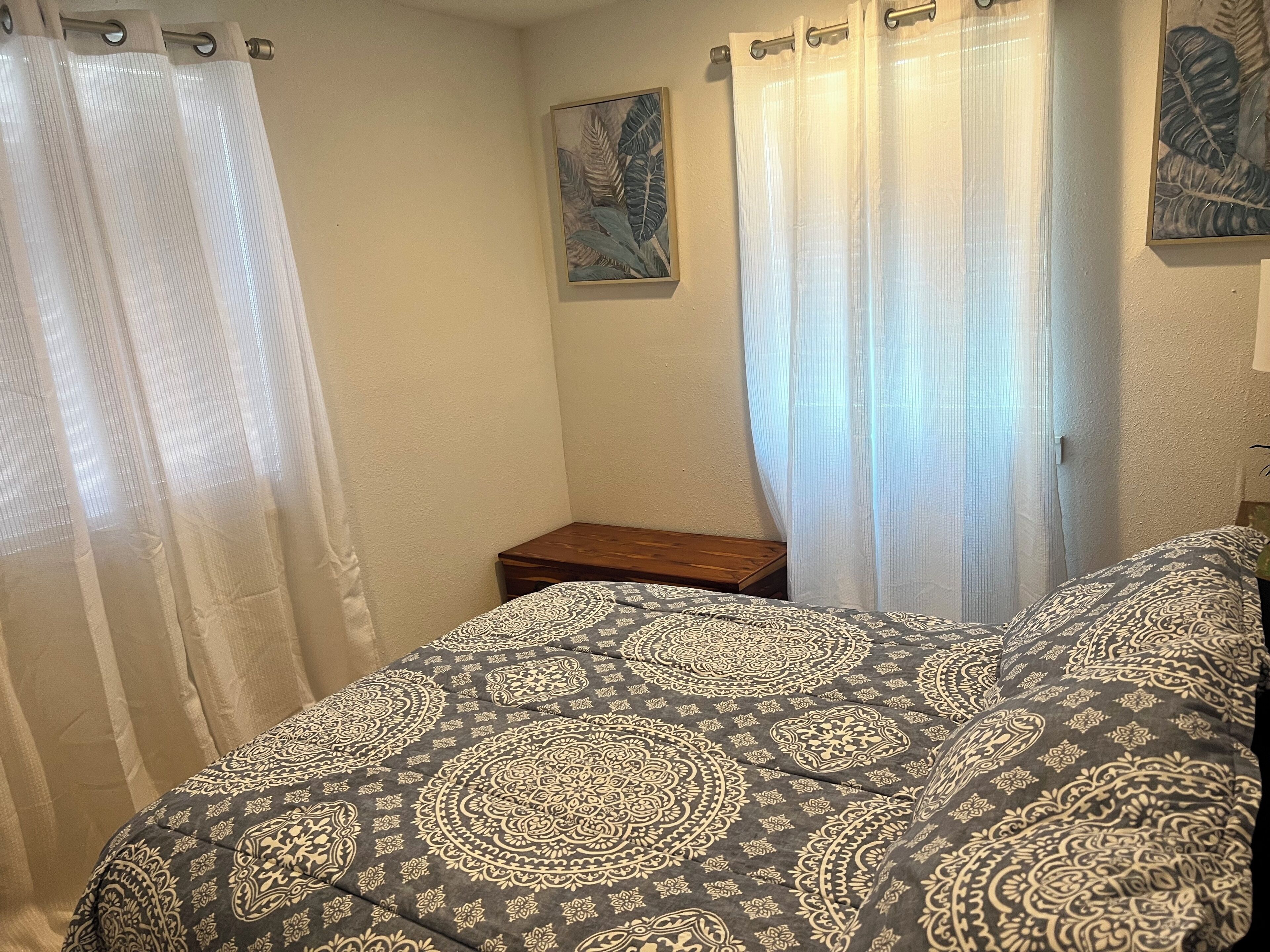 A bedroom with a bed, a nightstand, and a painting on the wall.