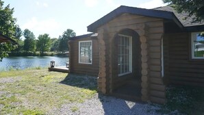 Una cabaña de troncos con un pequeño porche, una ventana y una puerta.