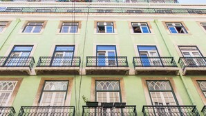 Un edificio de varios pisos con balcones, ventanas grandes y fachada verde.
