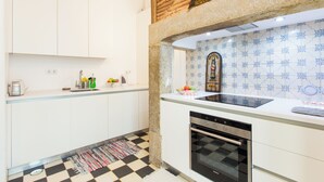 Una cocina moderna con armarios blancos, piso a cuadros, horno empotrado y salpicadero con diseño azul.