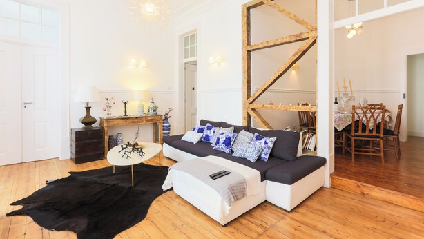 Un salón amplio con un sofá modular, un tapete de cuero negro y una mesa de comedor de madera con sillas.