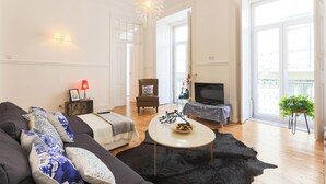 Una sala de estar moderna con un sofá, una mesa de centro, un televisor y un balcón con una planta.