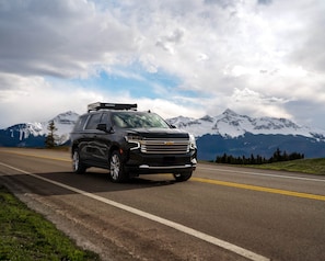 A black SUV on a road with snow-capped mountains in the background. - The Ice House: Luxury & Location w/ pool & hot tub (Telluride)