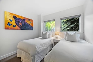A bedroom with two beds, a painting of a bear, and a window with a view of trees. - The Ice House: Luxury & Location w/ pool & hot tub (Telluride)