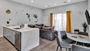 Eine moderne Küche mit einer Marmorinsel, grauem Sofa und Essbereich mit Stühlen.
