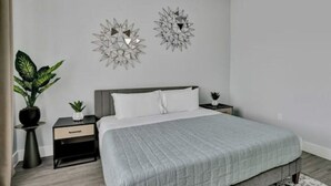 Ein modernes Schlafzimmer mit einem Bett, zwei Nachttischen, einer Topfpflanze und Wanddekoration.