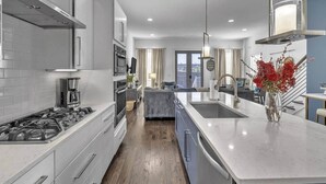 A modern kitchen with a central island, built-in oven, and stainless steel appliances.