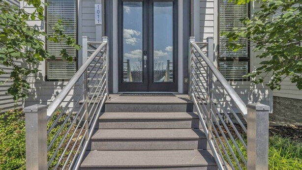 A building entrance with a double door, a staircase with metal railings, and a sign indicating the address.