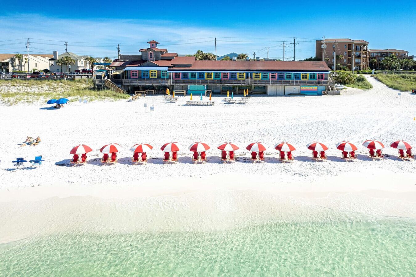 Un edificio sulla spiaggia, con una fila di ombrelloni e vista libera sull'oceano.