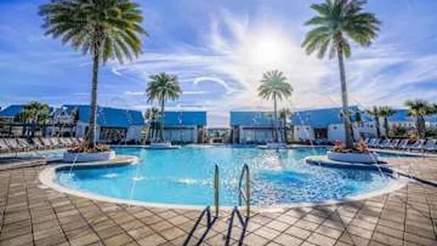 A pool area with palm trees, lounge chairs, and a clear sky. - 5 Mins from Beach with Private Golf Cart and Pool (Santa Rosa Beach)