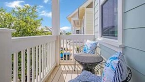 A covered porch with a white railing, a small table with chairs, and a view of a house and trees. - 5 Mins from Beach with Private Golf Cart and Pool (Santa Rosa Beach)
