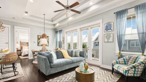 A spacious living room with a blue sofa, a round coffee table, and a ceiling fan. - 5 Mins from Beach with Private Golf Cart and Pool (Santa Rosa Beach)