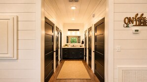A hallway leading to a kitchen with dark cabinets and a wooden floor. - Romantic Cabin with Hot Tub, Fire Pit, BBQ & Fenced Yard (Broken Bow)