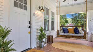 A porch with a swing, a door, and a doormat. - Peaceful Lake House - Sleeps 10, Games, Fishing & Near Downtown/Airport/BJCC (Birmingham)