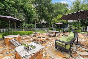 An outdoor patio with stone flooring, a fire pit, wicker furniture, and umbrellas. - 30A Private Gulf Retreat| Bay Access| Patio | BBQ (Santa Rosa Beach)