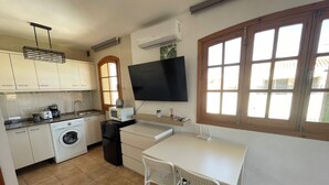 A compact kitchen with a washing machine, a microwave, and a TV mounted on the wall. - Mar Menor Studio Cielo - pet-friendly, pool and wi-fi (Cartagena)