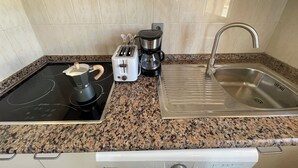 A kitchen with a granite countertop, a stove, a toaster, a coffee maker, and a stainless steel sink. - Mar Menor Studio Cielo - pet-friendly, pool and wi-fi (Cartagena)