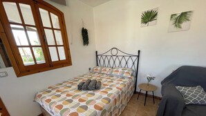 A bedroom with a bed, a small round table, a sofa, and a window with curtains. - Mar Menor Studio Cielo - pet-friendly, pool and wi-fi (Cartagena)