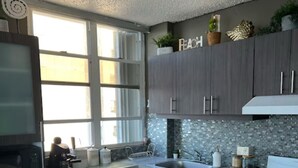 Een moderne keuken met donkere kastjes, een witte oven en een groot raam dat voor natuurlijk licht zorgt.