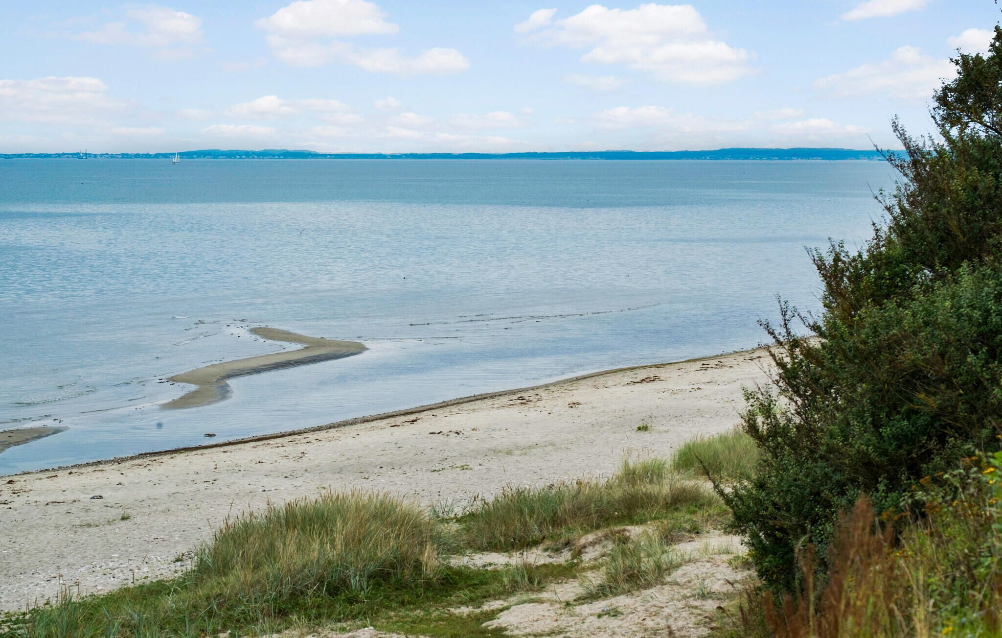 En strand med krystalklart vand og fjerne kystlinjer.