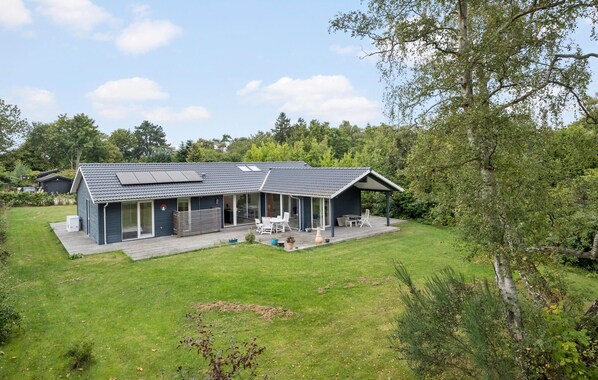 A modern house with a large deck, a covered outdoor seating area, and a solar panel on the roof. - Nice home in Dronningmølle with sauna (Dronningmølle)