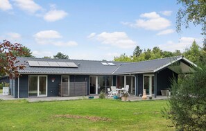 A modern house with a sloped roof, large windows, and a covered patio area. - Nice home in Dronningmølle with sauna (Dronningmølle)