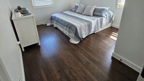 A bedroom with a bed, a ceiling fan, a nightstand, and a window with blinds. - Raytown Ranch - Mahome Away from Home (Raytown)