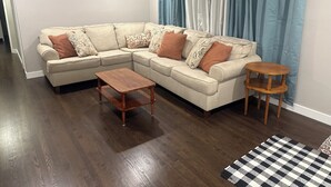 A living room with a sectional sofa, a wooden coffee table, and a small wooden side table. - Raytown Ranch - Mahome Away from Home (Raytown)