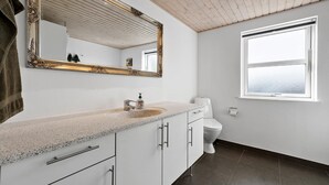 A bathroom with a large mirror, a sink, a toilet, and a window. - 3 bedroom amazing home in Slagelse (Slagelse)