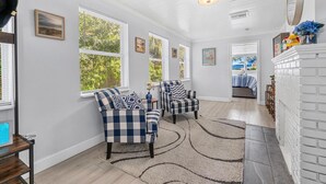 A spacious living room with a fireplace, large windows, and a cozy seating area.