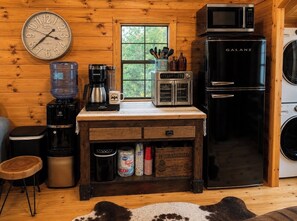 A compact kitchen with a Galanz refrigerator, a coffee maker, a microwave, and a water dispenser.