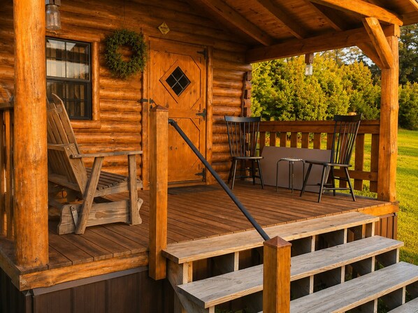 A wooden cabin with a porch, a door with a window, and a chair.