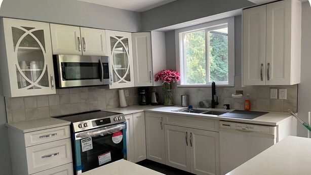 A kitchen with white cabinets, a microwave, a stove, and a sink. - Superb 3-bedroom farmhouse in Abbotsford (Abbotsford)