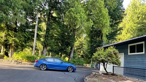A blue car parked in a driveway with a house and trees in the background. - Superb 3-bedroom farmhouse in Abbotsford (Abbotsford)