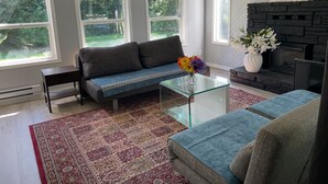 A modern living room with a grey sofa, a glass coffee table, and a red patterned rug. - Superb 3-bedroom farmhouse in Abbotsford (Abbotsford)