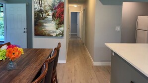 A kitchen with a dining area, a painting on the wall, and a wooden floor. - Superb 3-bedroom farmhouse in Abbotsford (Abbotsford)