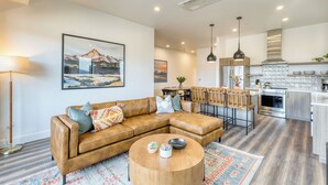 A modern living room with a leather sectional sofa, a round coffee table, and a dining area with bar stools.