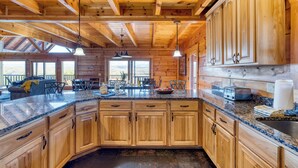 A wooden cabin kitchen with granite countertops, wooden cabinets, and pendant lighting.