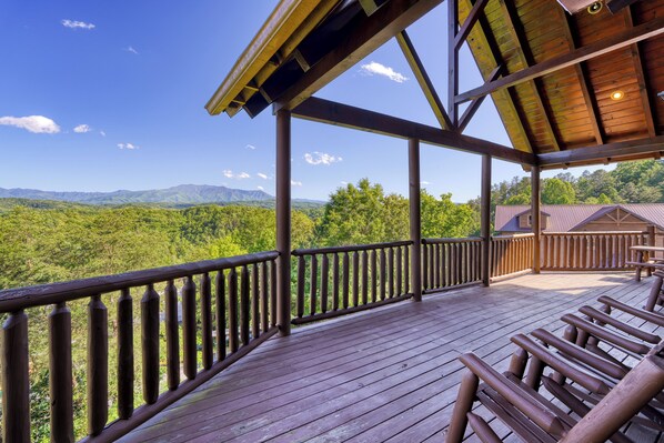 A wooden deck with a view of green mountains and a clear sky.