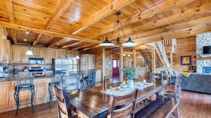 A spacious kitchen with wooden cabinets, a large island, and a dining area with wooden chairs and a table.