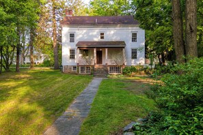 A two-story white house with a front porch, a stone pathway leading to the entrance, and a well-maintained lawn.