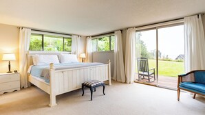 Una camera da letto con un letto, un comodino e vista su un giardino tramite una porta scorrevole.
