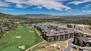 Un quartier résidentiel avec des maisons modernes, un terrain de golf et, en arrière-plan, un paysage montagneux.