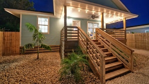 A house with a wooden staircase leading to a covered porch, a fan, and string lights. - Aloha Ohana by AvantStay | Private Pool Near Beach (Port Aransas)