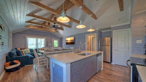 A spacious kitchen with a large island, wooden beams, and pendant lighting. - Aloha Ohana by AvantStay | Private Pool Near Beach (Port Aransas)