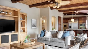 A living room with a grey sofa, wooden coffee table, and a TV on a wooden cabinet. - Wavebreak by AvantStay | Close to Beaches/Surfing (Solana Beach)