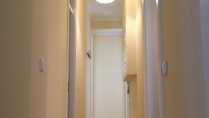 Een smalle gang met houten vloer en lichtgekleurde muren.