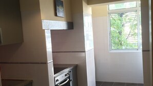 Een keuken met een inbouwoven, een hanglamp en een raam dat voor natuurlijk licht zorgt.