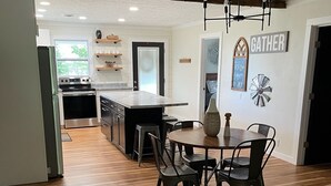 A modern kitchen with a central island, wooden flooring, and a dining area with a round table and chairs. - Oxbow Overlook: Ohio River Bend Views, Private Pond, Pets Welcome (Magnet)