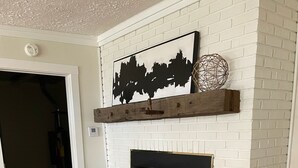 A white brick fireplace with a black mantel, a woven basket, and a framed sign. - Oxbow Overlook: Ohio River Bend Views, Private Pond, Pets Welcome (Magnet)